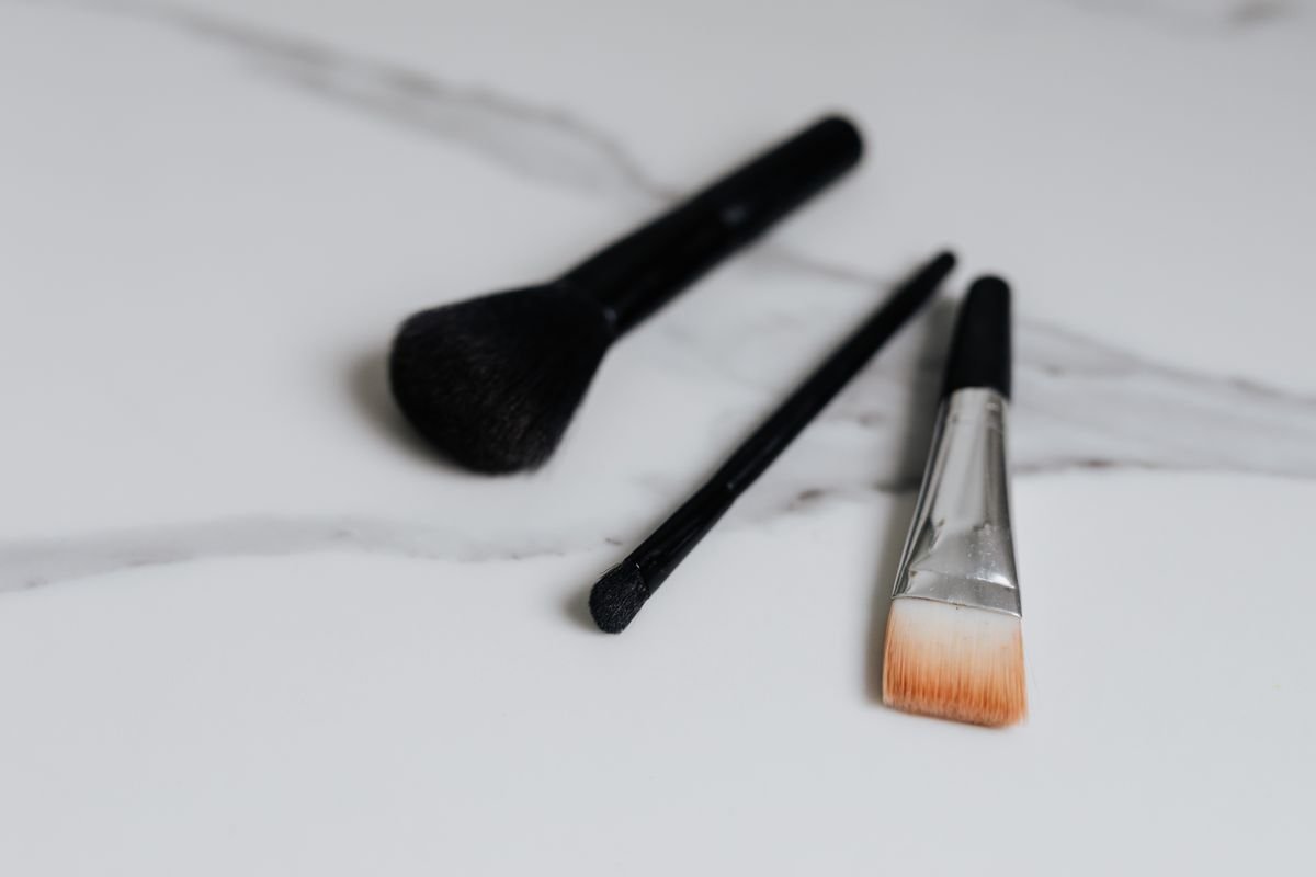 Makeup brushes lying separately on a pale marble surface