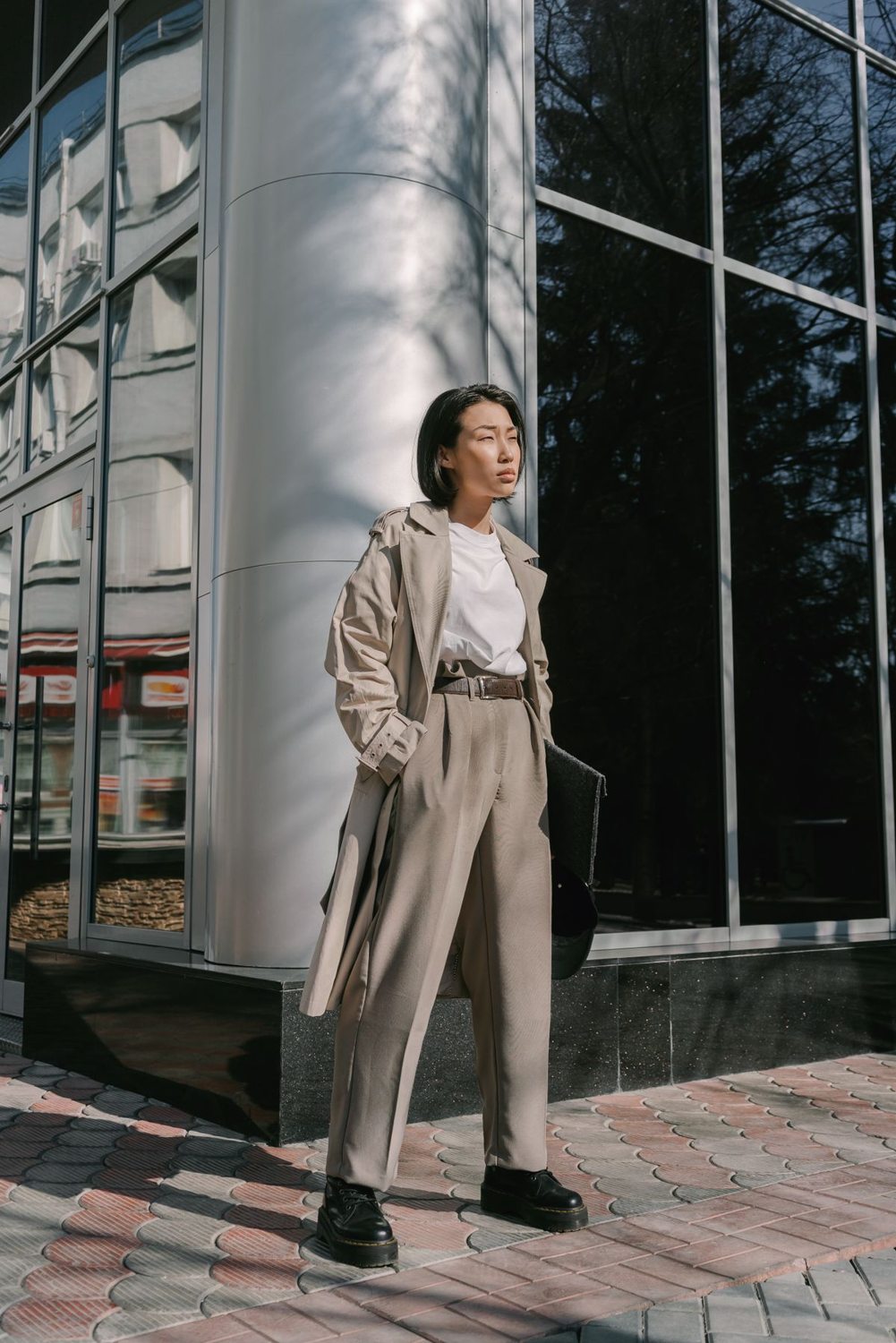 Woman wearing a long trench coat outside an office building