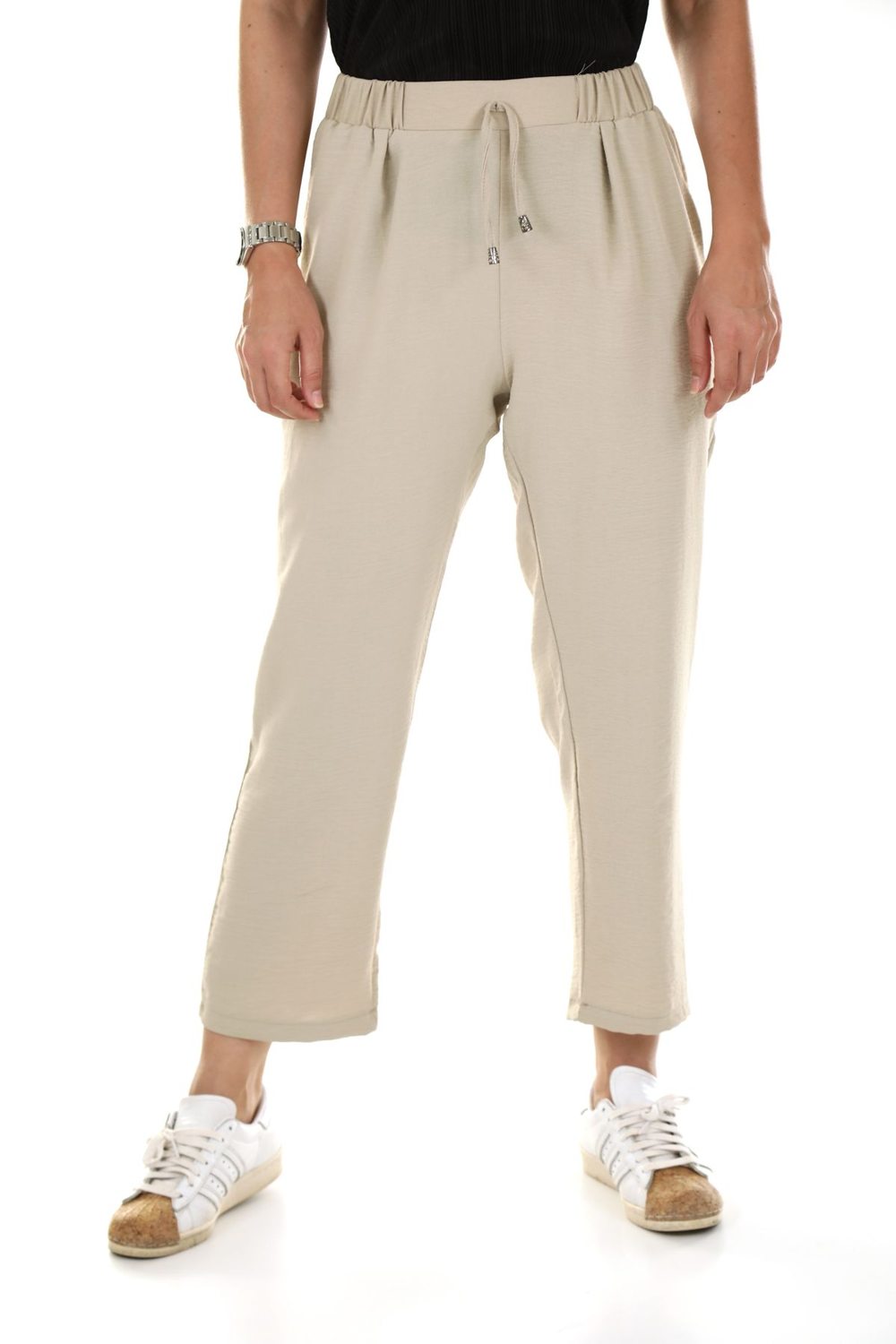 Ankle-length beige trousers worn with white trainers