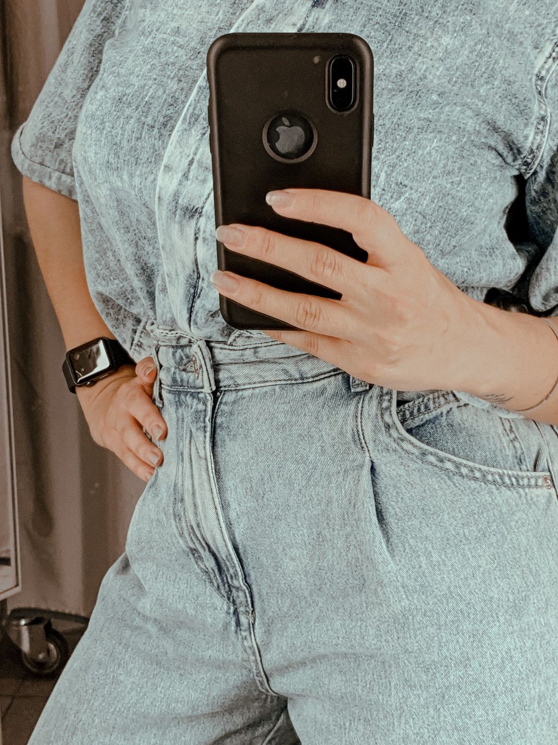 Woman photographing her denim outfit in a mirror
