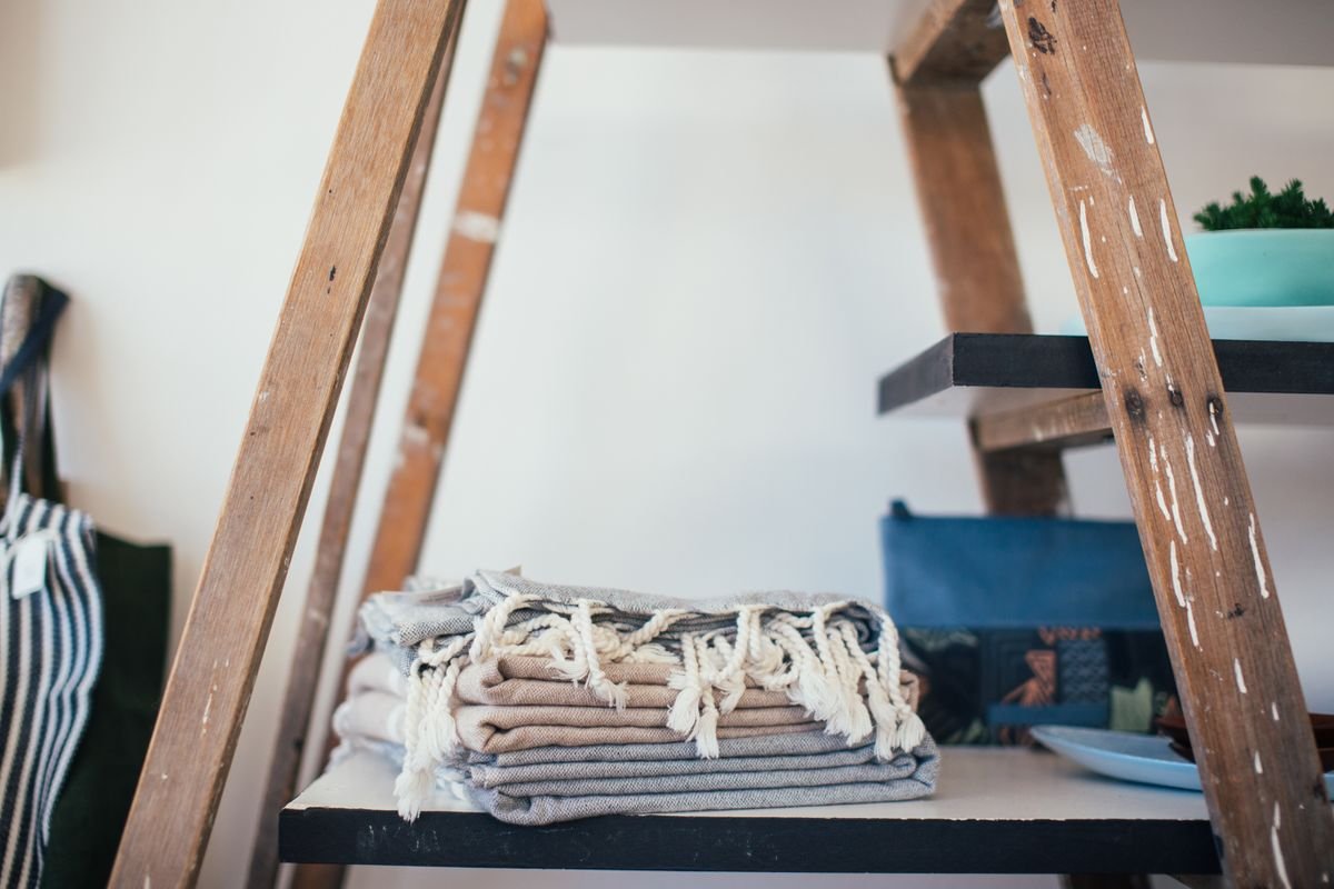 Folded cotton towels stacked on a wooden shelf