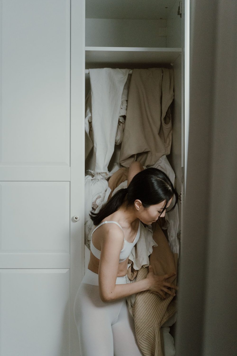 Woman sorting clothes in a full wardrobe
