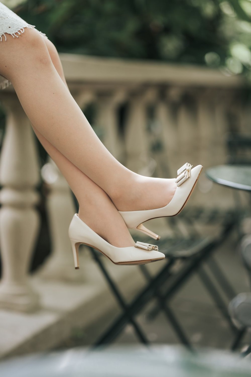 White occasion heels with bows worn outdoors