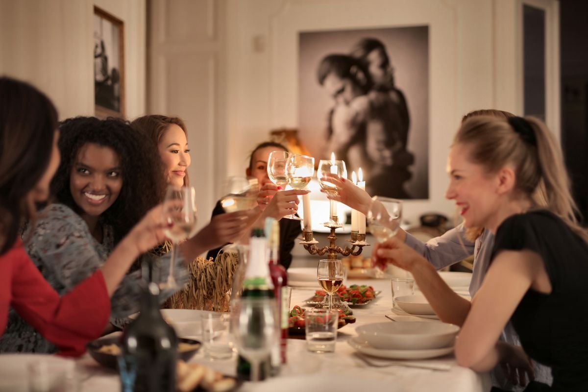 Friends seated around a dining table with plates and glasses