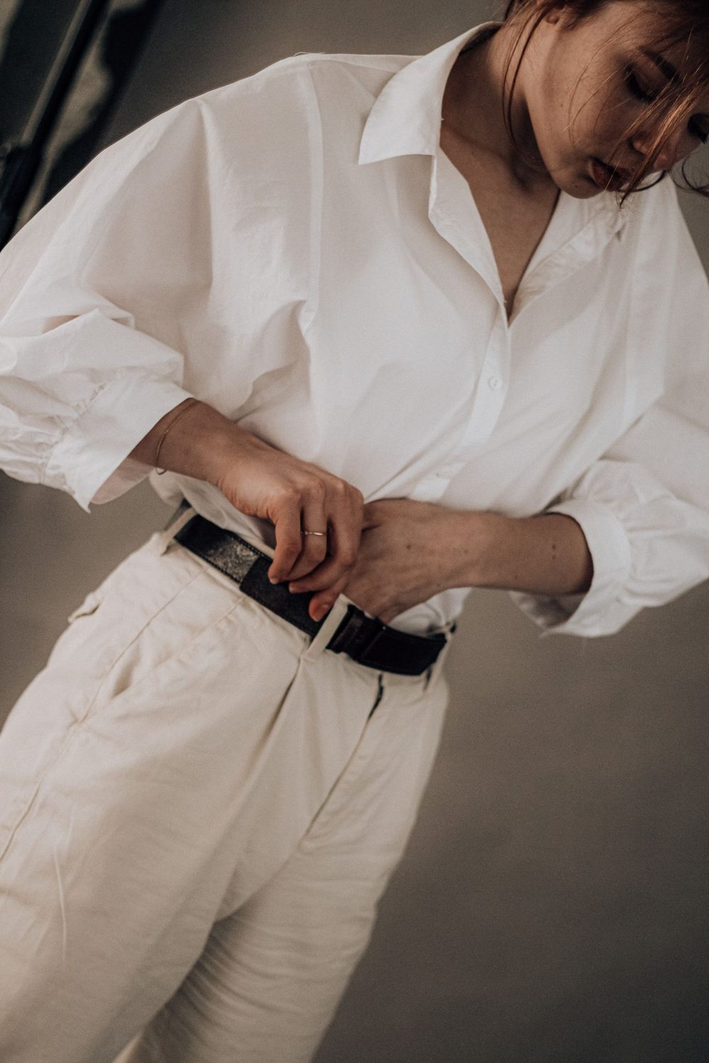 Woman tucking a white shirt into light trousers