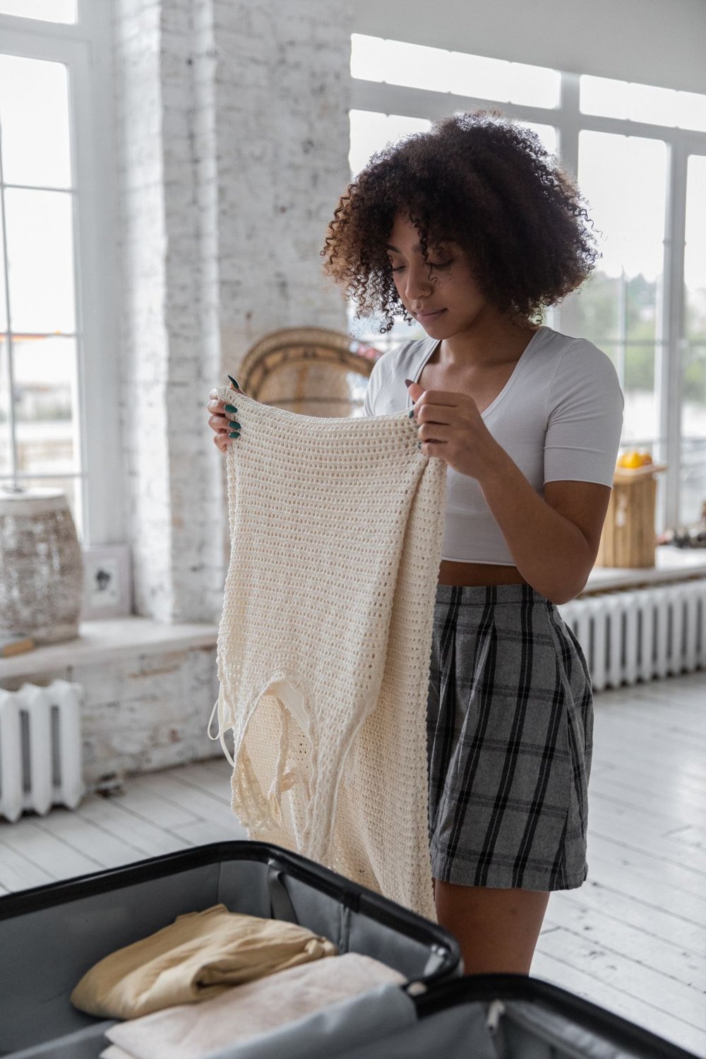 Woman choosing clothes to pack in an open suitcase